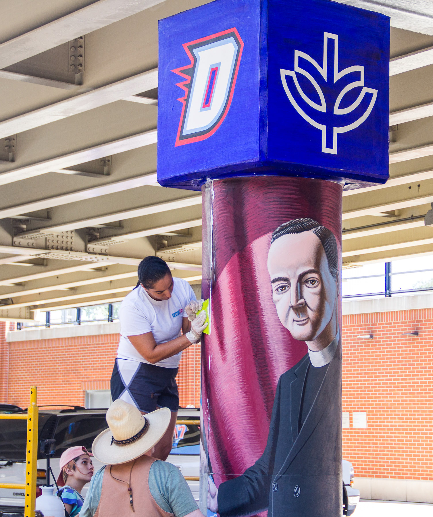 Students help install the new murals on the CTA 'L' pillars as part of the "The Story of the Little School Under the 'L'" art project led by Brother Mark Elder, C.M. (DePaul University/Russell Dorn)